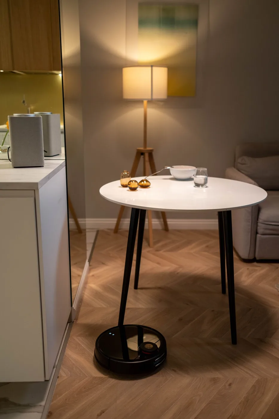 A compact apartment living area with a table, sofa, and floor lamp
