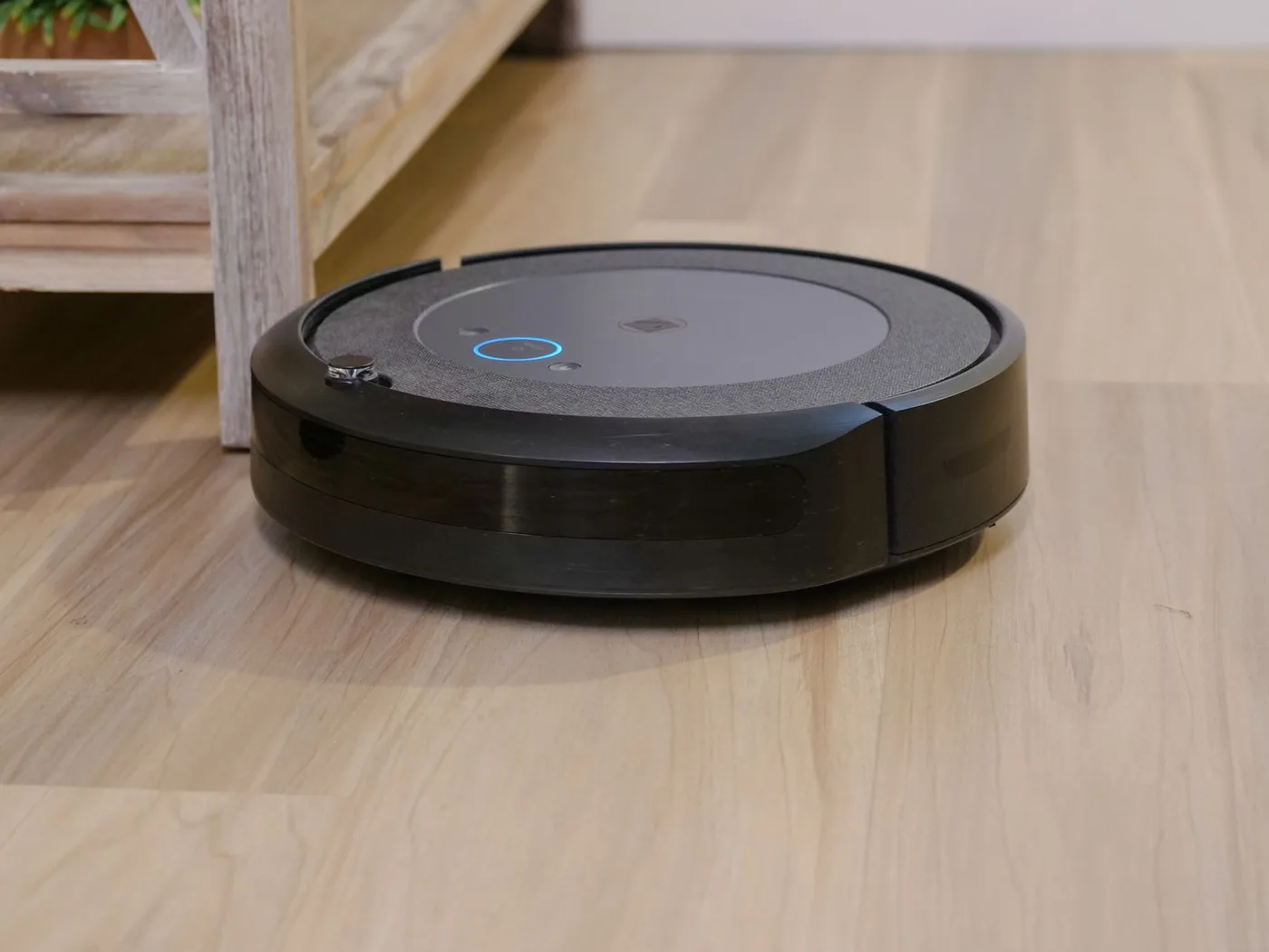 A round robot vacuum on a wooden household floor