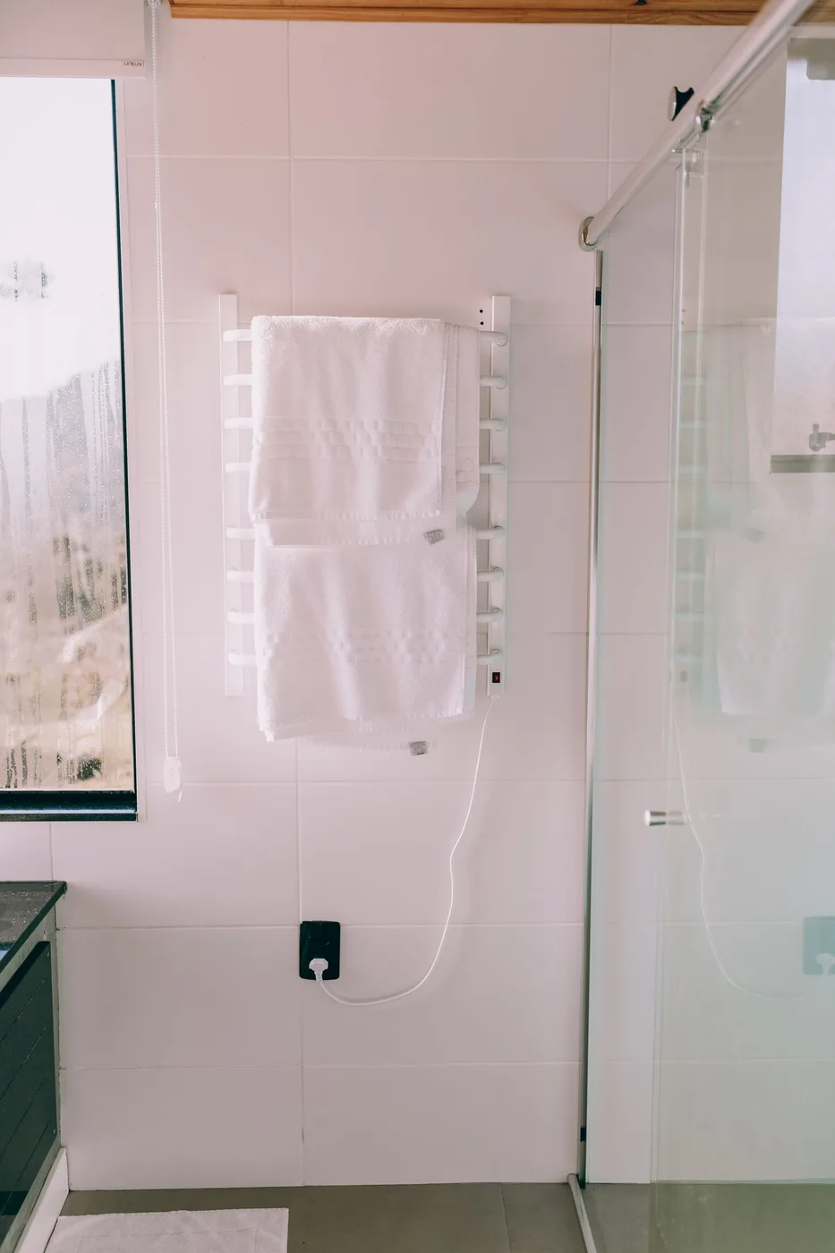 A bathroom with a shower and wall mounted towel storage